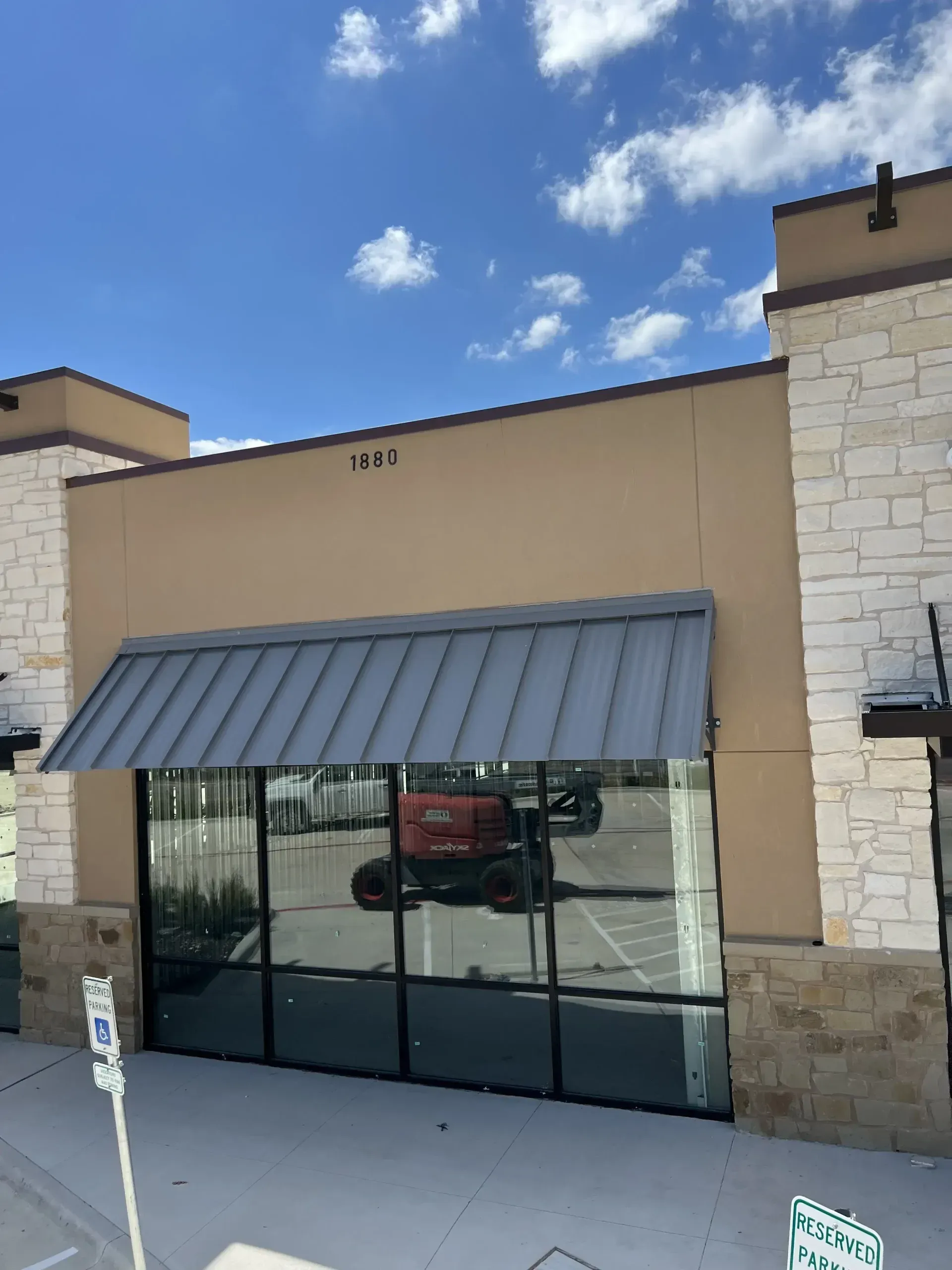 Exterior of commercial building with tan walls, large windows, and a metal awning.