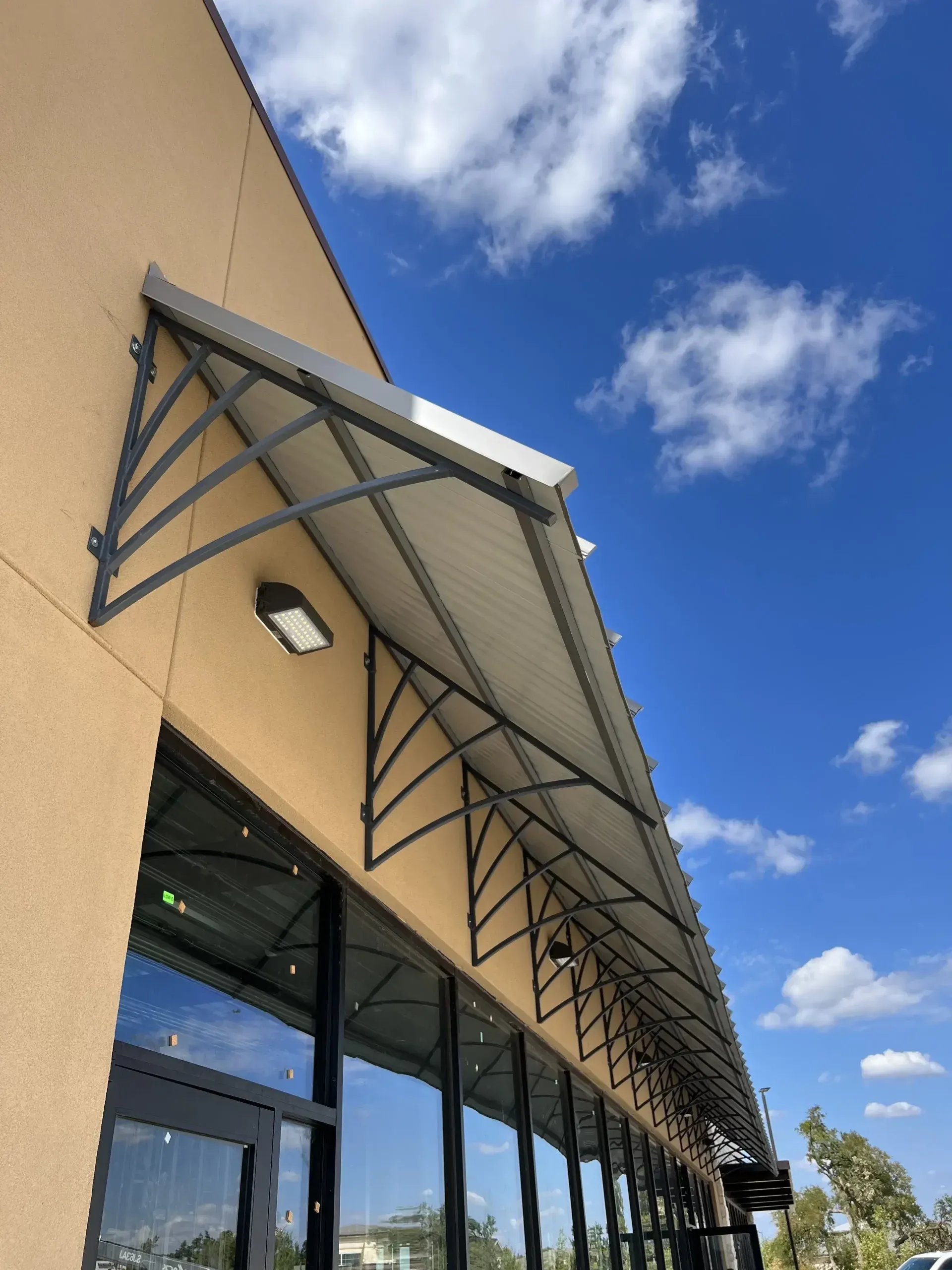 Tan building with long awning, glass windows, and blue sky.
