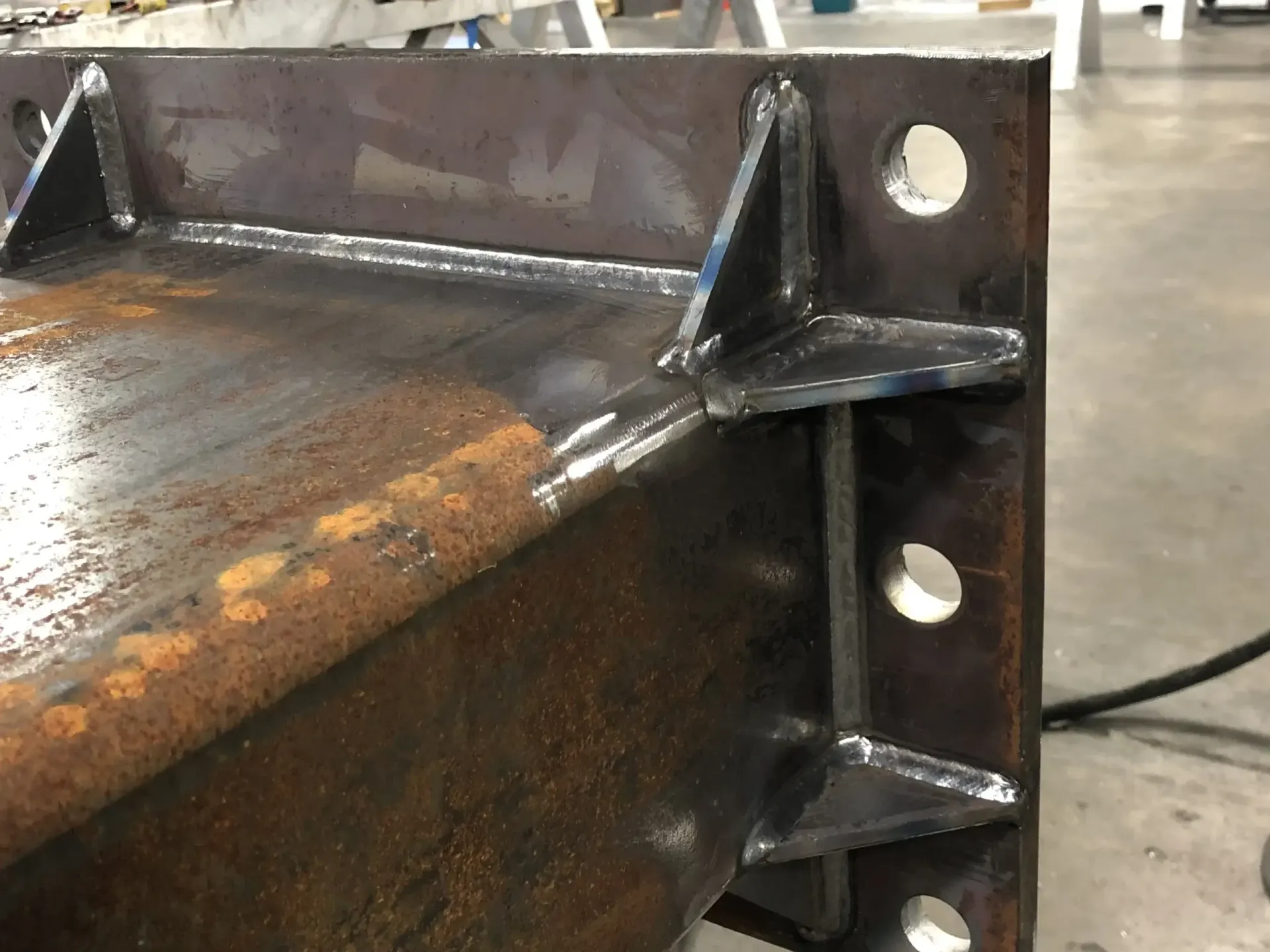 Welded steel beam with gussets and bolt holes, showing construction detail.