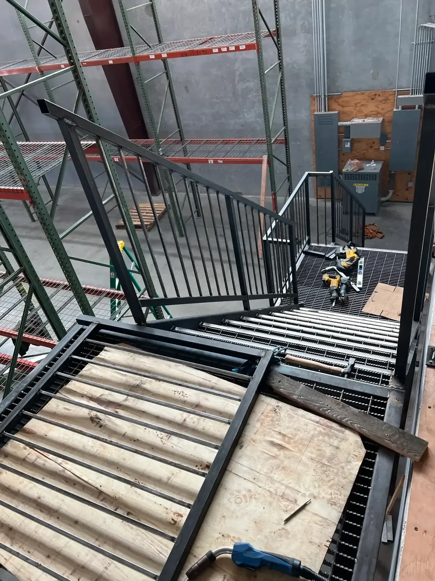 Metal stairs with railing in an industrial warehouse; construction in progress.