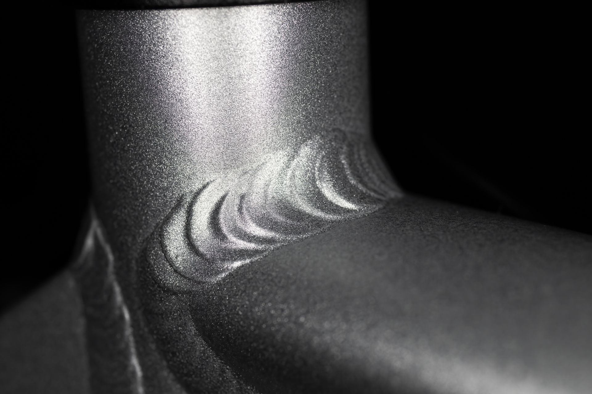 Close-up of a welded joint on a silver-colored metal bicycle frame.