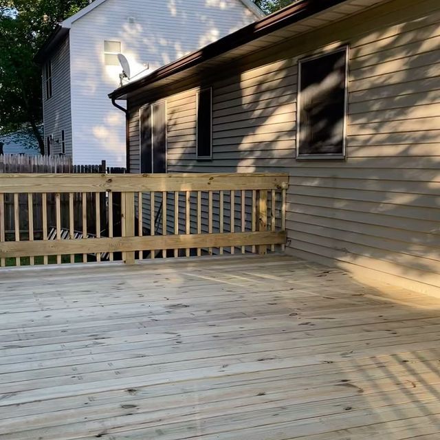 A wooden deck with a fence in front of a house