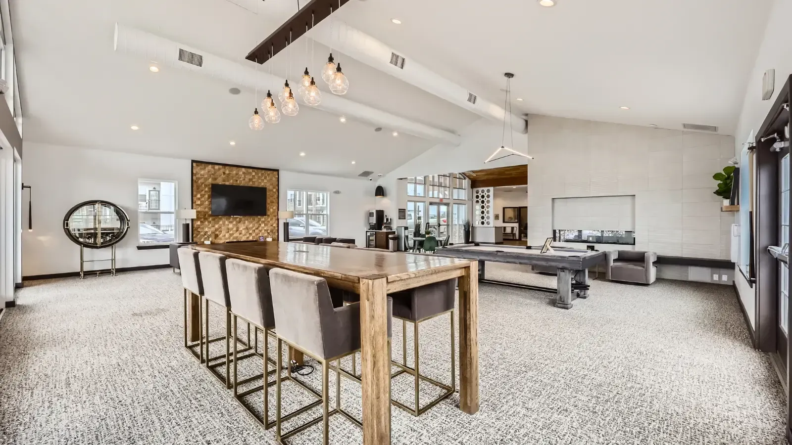 Bright communal lounge with a long wooden high table, seating, a TV wall, and a billiards table.