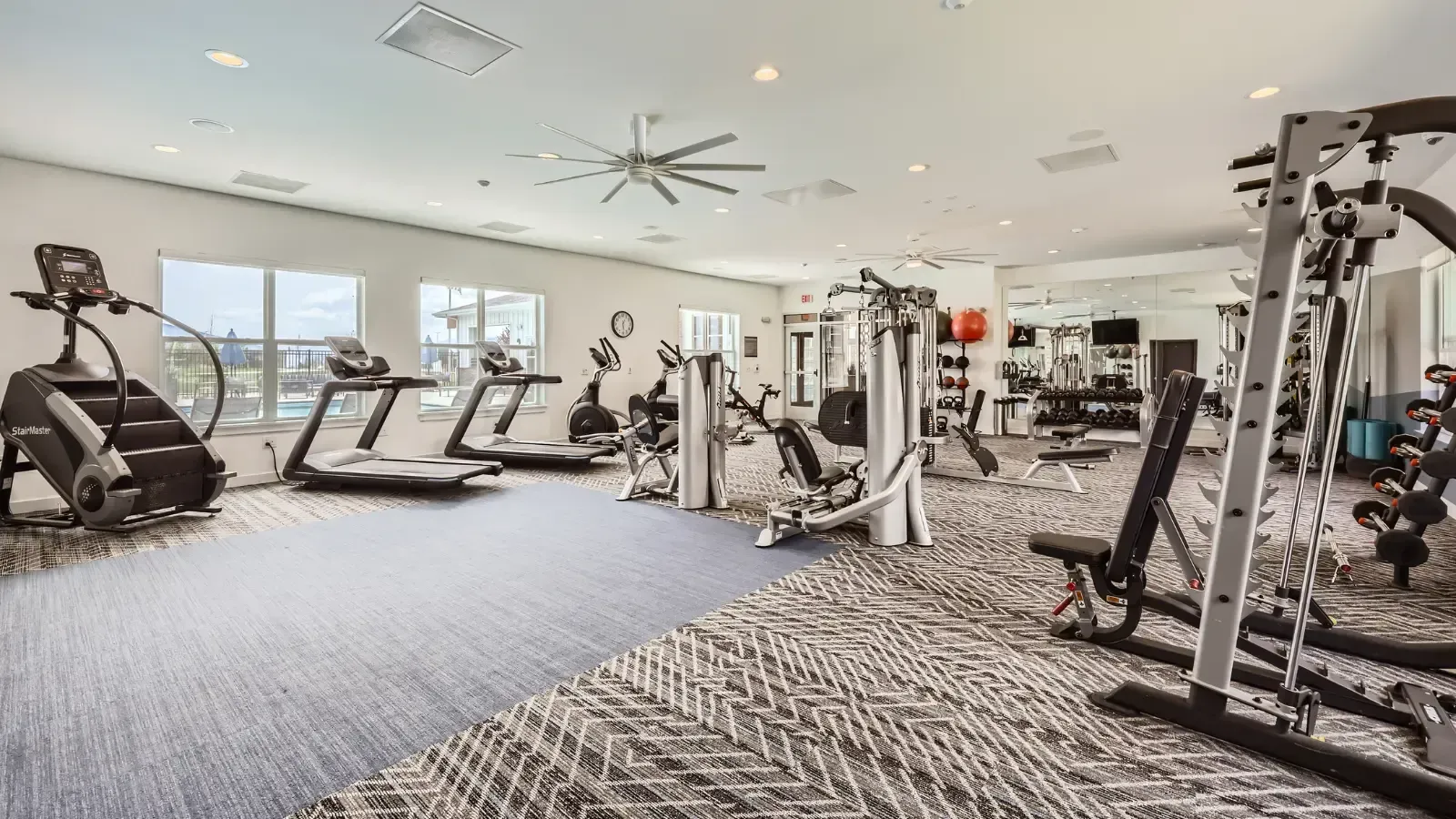 Well-equipped community fitness center with cardio machines, weight machines, and mirrors.