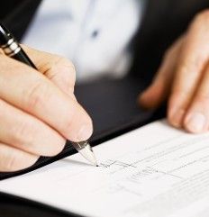 A person is writing on a piece of paper with a pen.