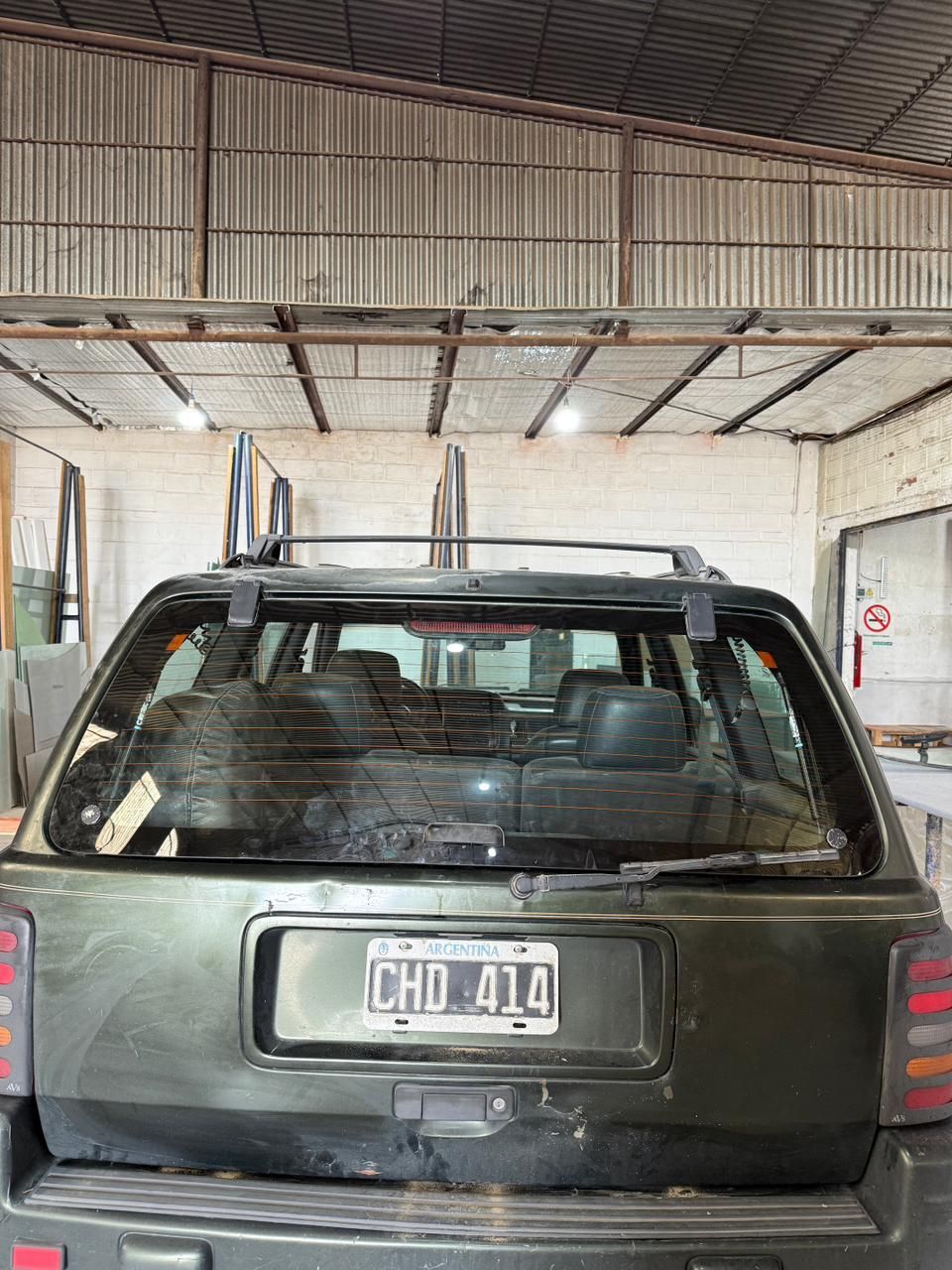 Camioneta verde con la ventana trasera rota, en un garaje.