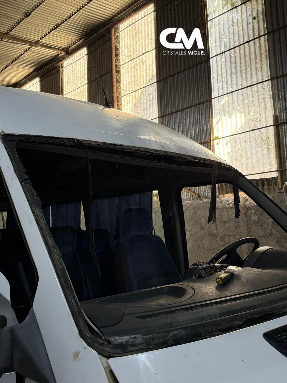 Interior de camioneta blanca con parabrisas y asientos visibles; estacionada en el interior.