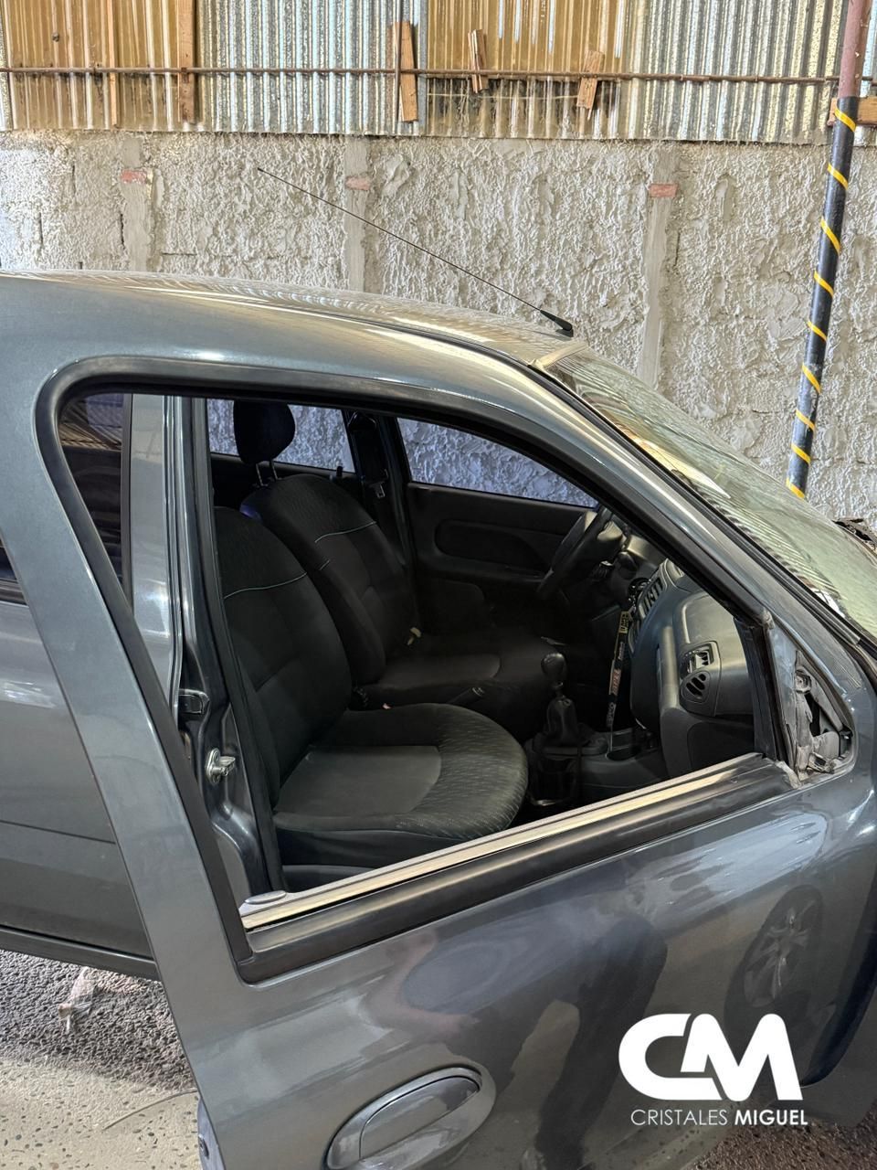 Interior de coche gris, la puerta abierta revela los asientos y el volante.
