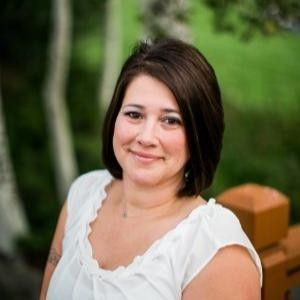The woman is wearing a black turtleneck and smiling for the camera.