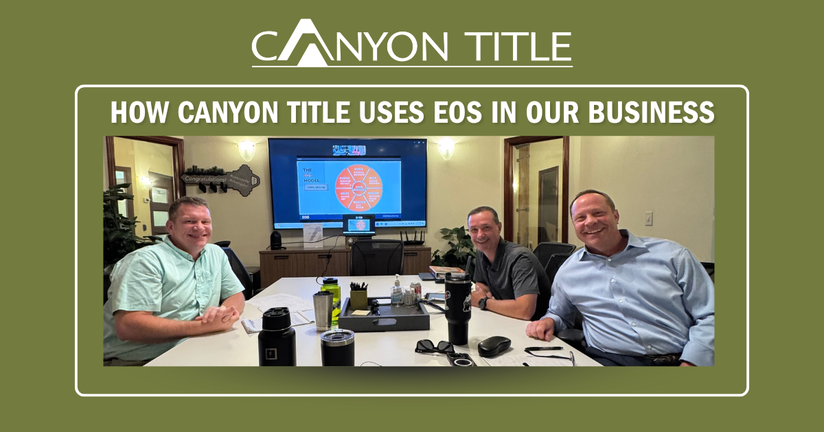 Three men are sitting at a table in a conference room.