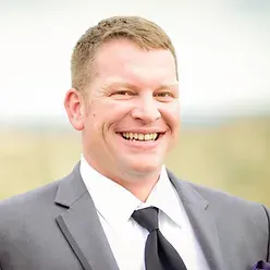 A man in a suit and tie is smiling for the camera.