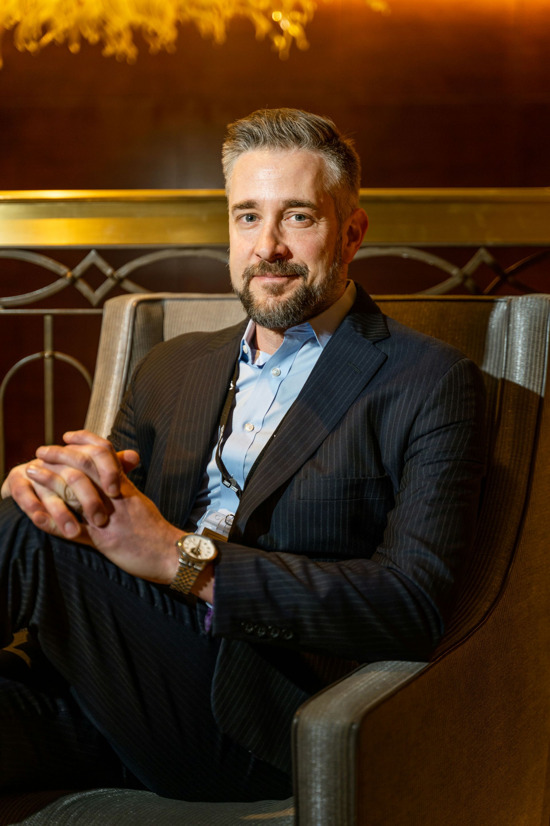 A man in a suit is sitting in a chair with his legs crossed.