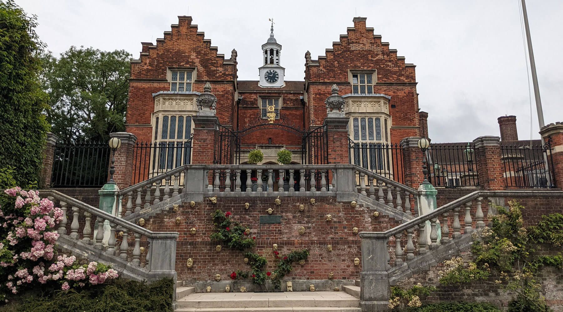 Red brick mansion with stone staircase and a clock tower.