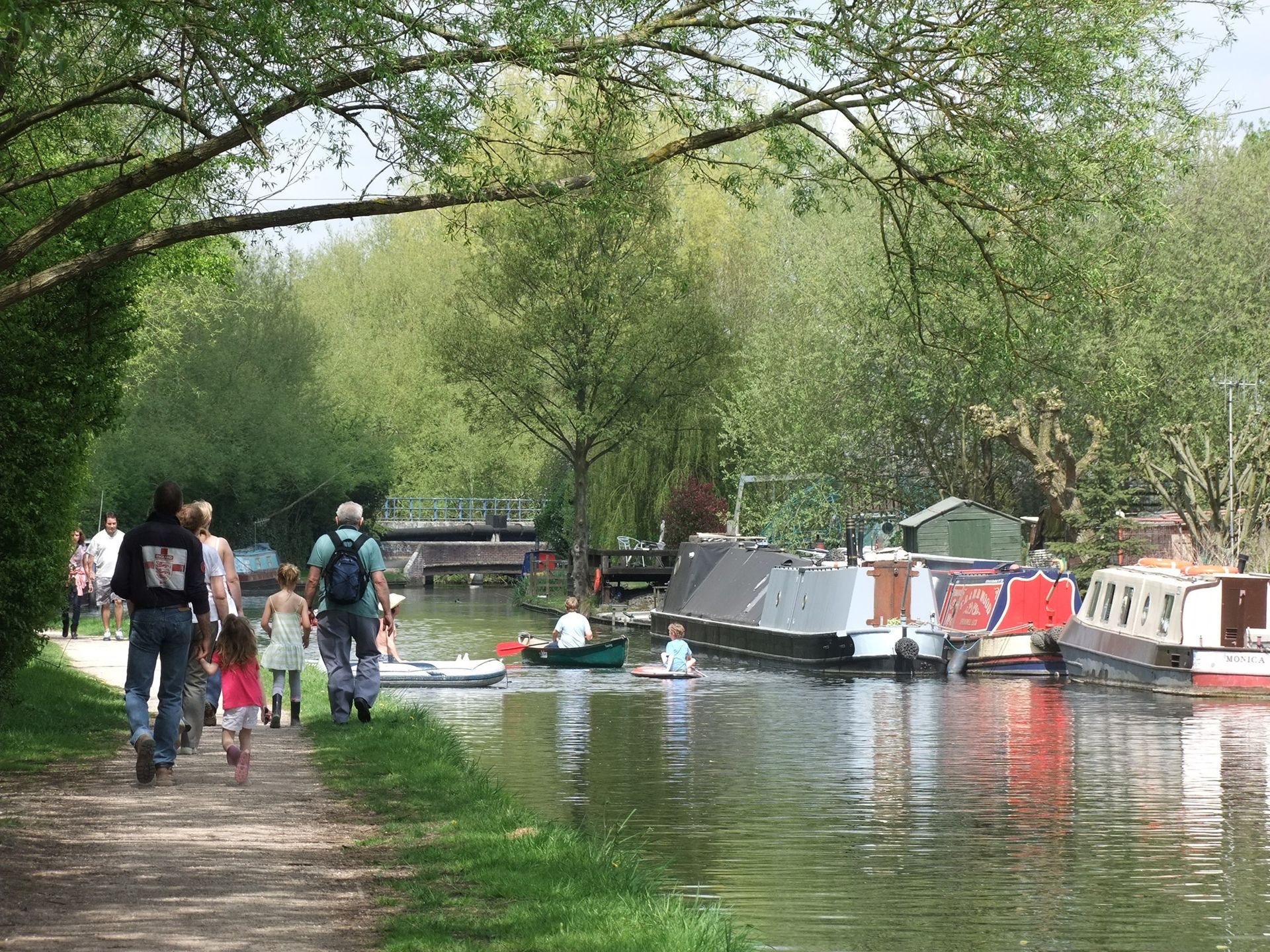 Stone cottages line a river in a Cotswold village, a small bridge in the foreground reflecting the colorful sunset sky.