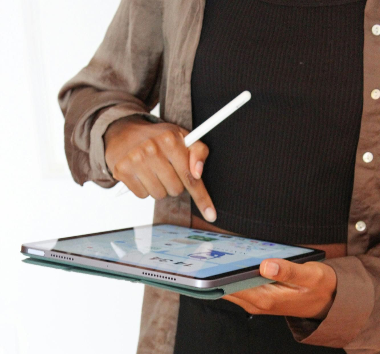 Person using a stylus to interact with a tablet. The tablet is in a folio case.