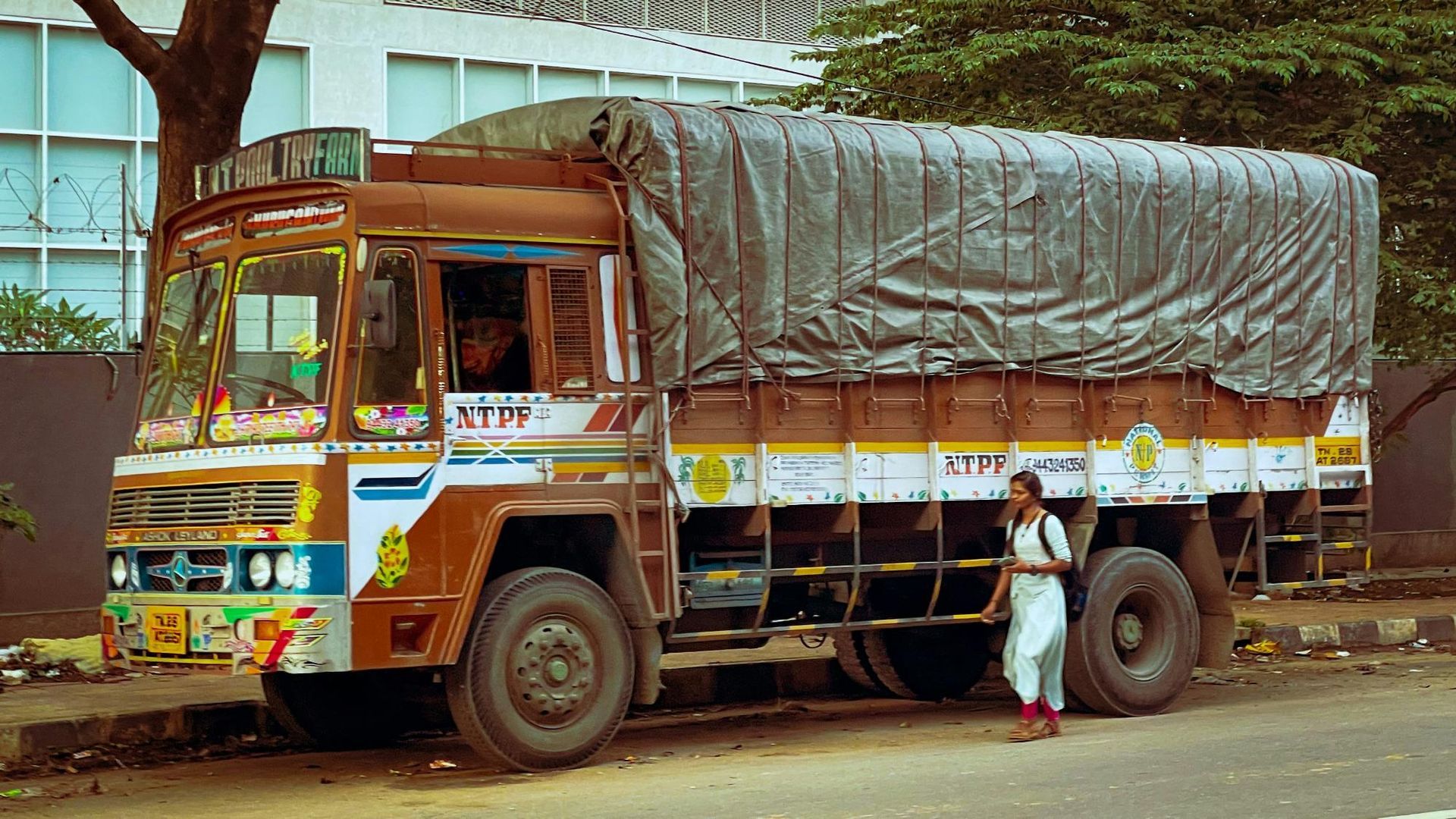 Large, weathered cargo truck parked on a city street; a person walks by.