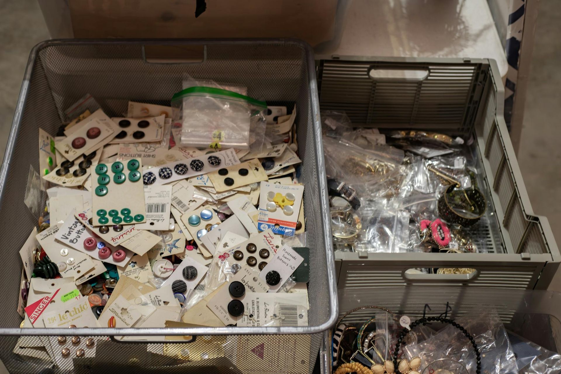 Two bins filled with sewing notions: buttons and jewelry.
