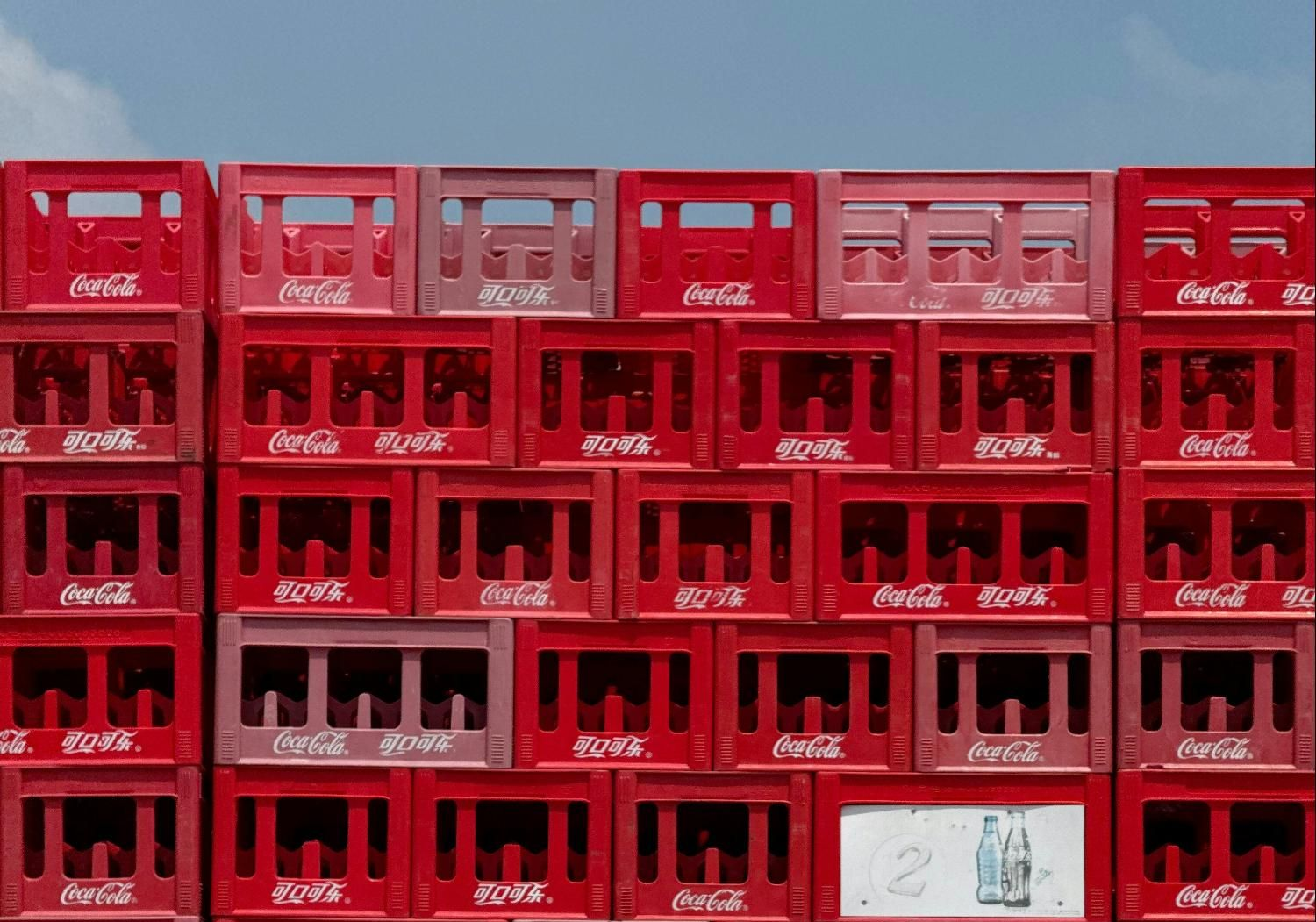 Red Coca-Cola crates stacked against a blue sky.