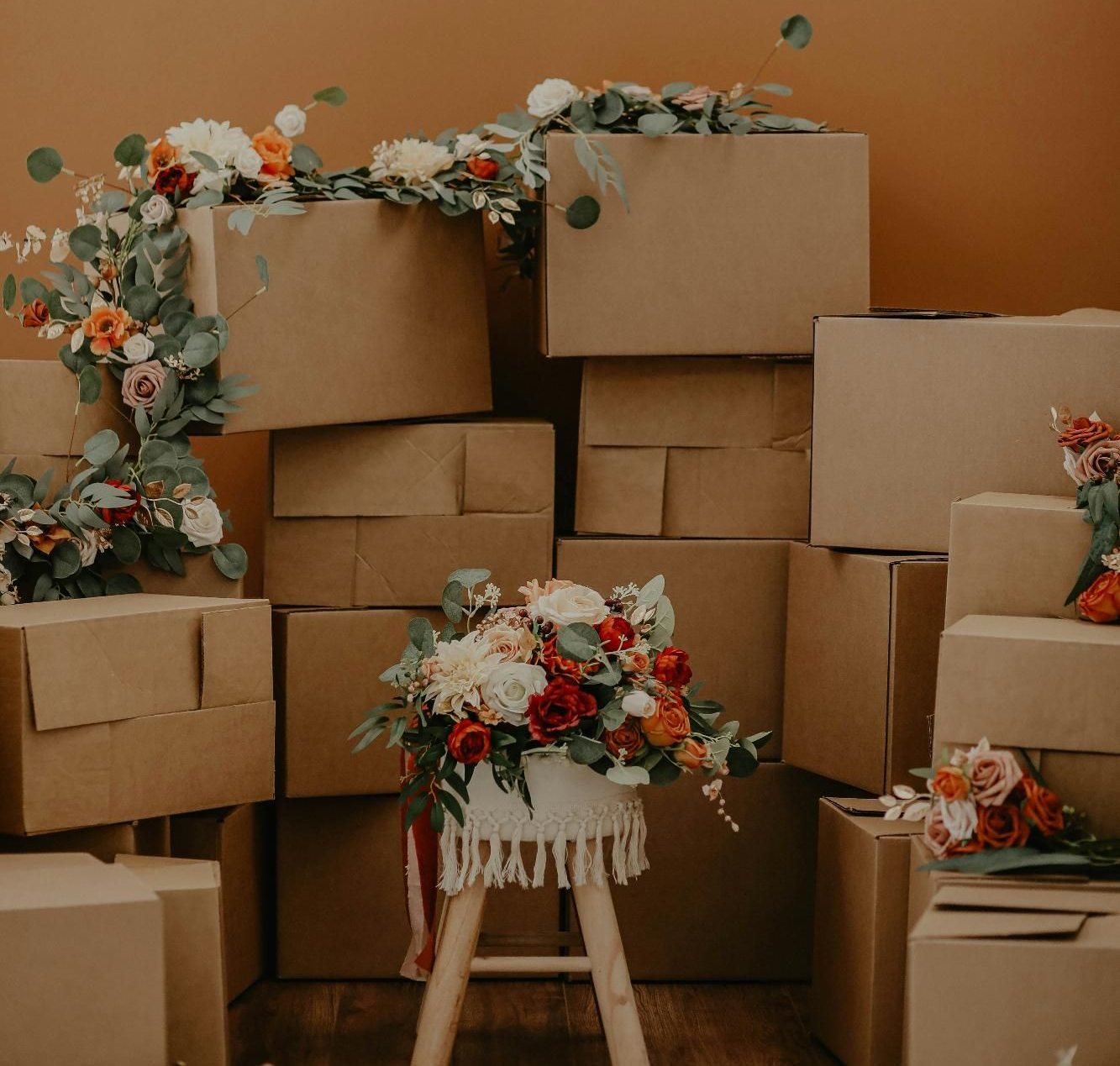 Cardboard boxes stacked with floral arrangements on a stool.