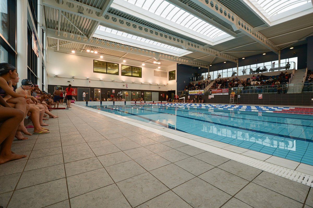 A canal with a floating building under a bridge at sunset. Golden light reflects on the water.