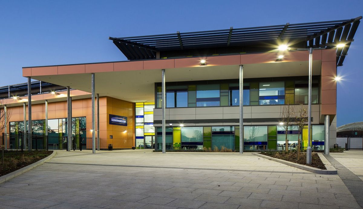 Ruins of a red brick building with arched windows against a clear blue sky.