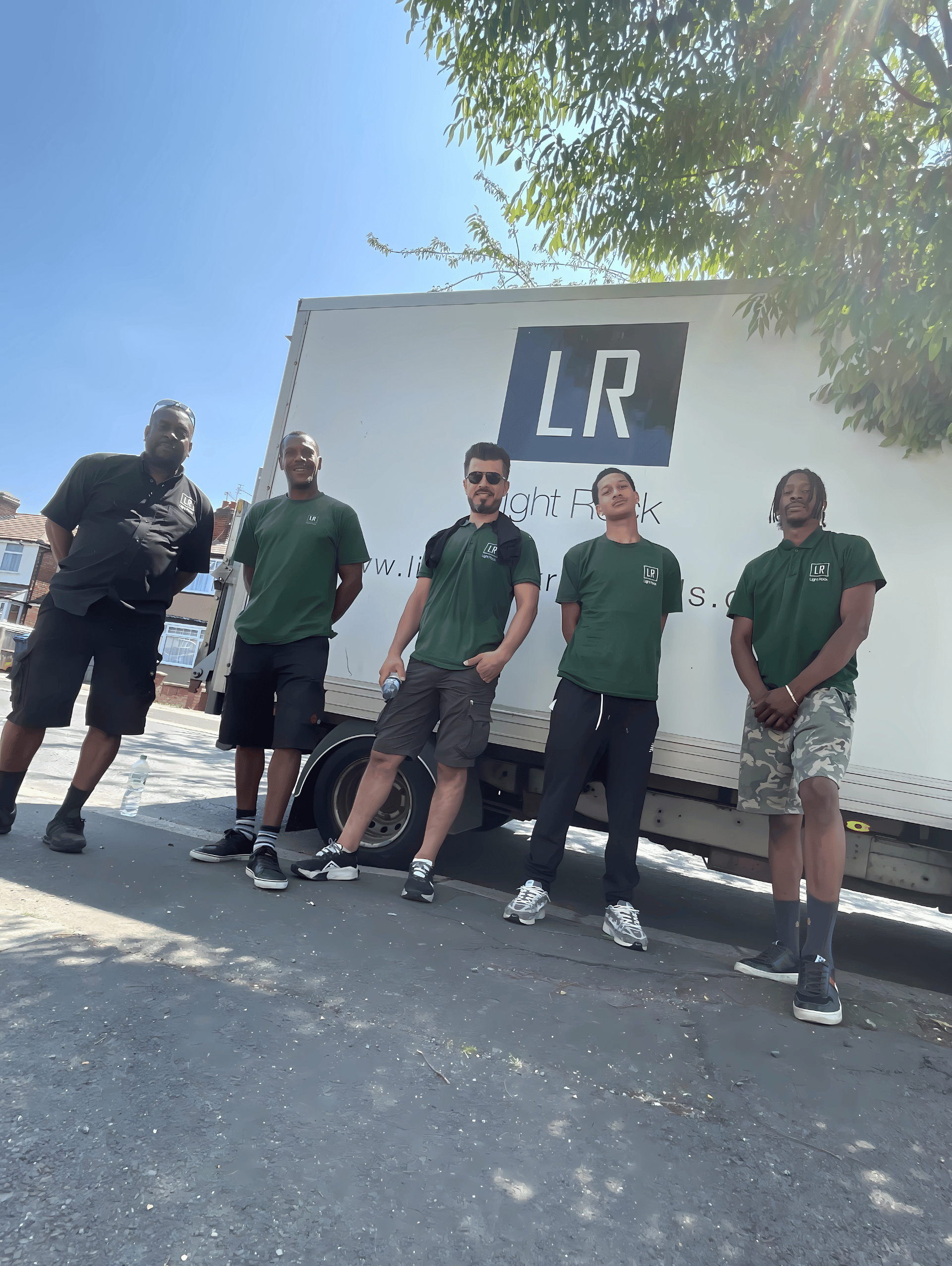 Five movers in green shirts stand in front of a white truck with 