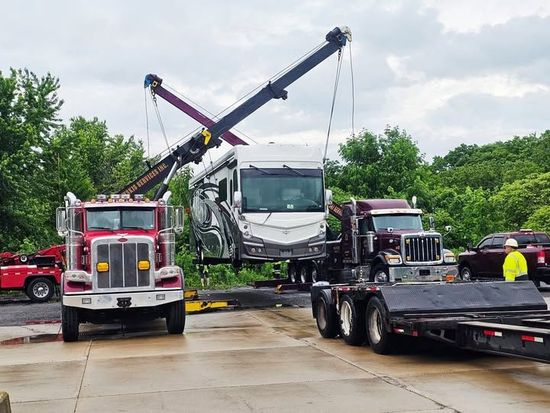 A white car is being lifted by a crane at night.