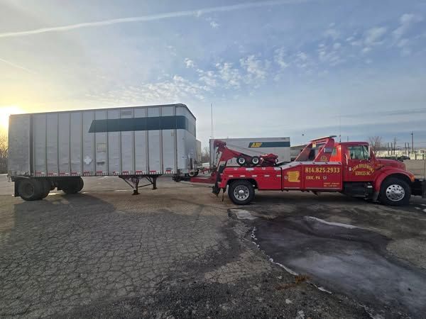 A white truck is being towed by a crane on the side of the road.