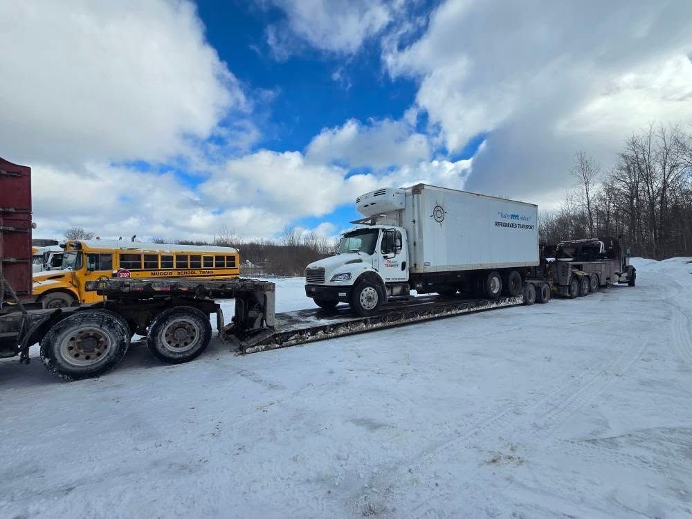A group of semi trucks are driving down a snow covered highway.
