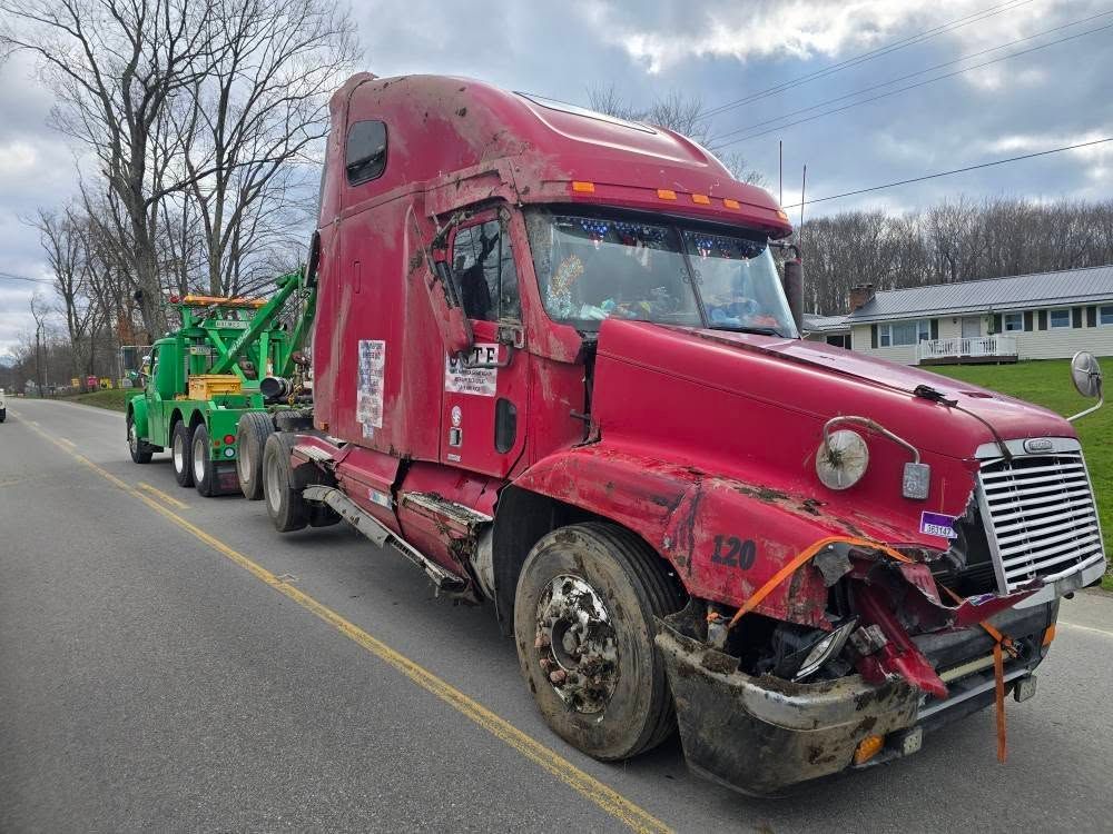A semi truck is stuck in the snow on a snowy road.