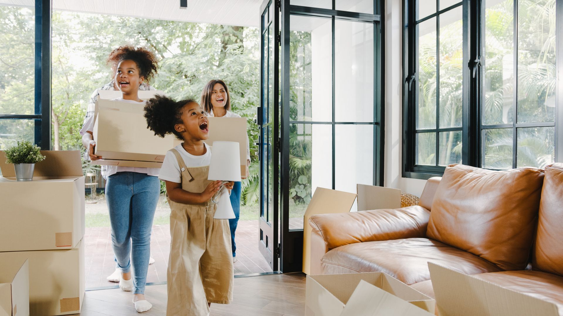 A family is moving into a new home carrying cardboard boxes.