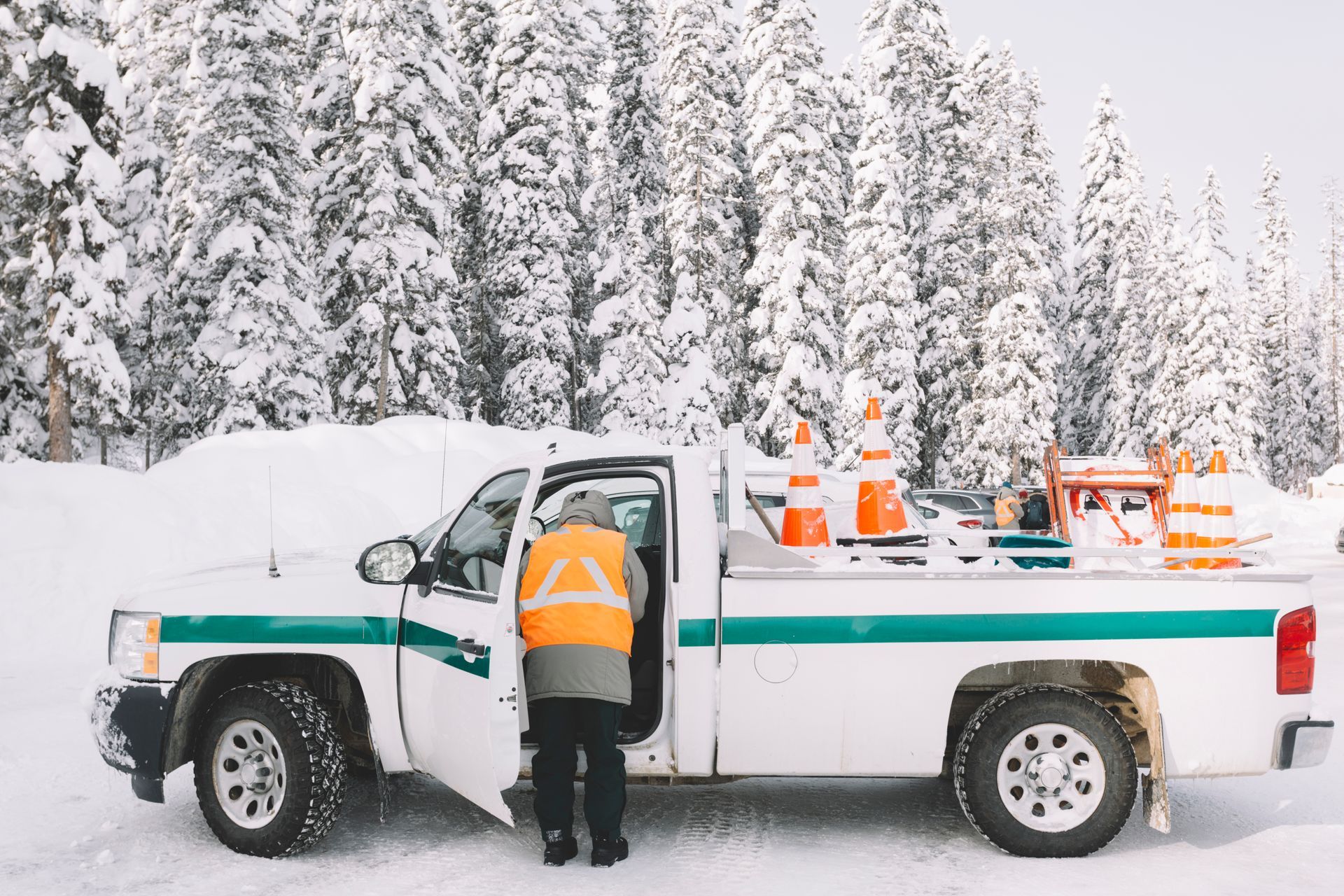 A man is getting out of a truck in the snow.