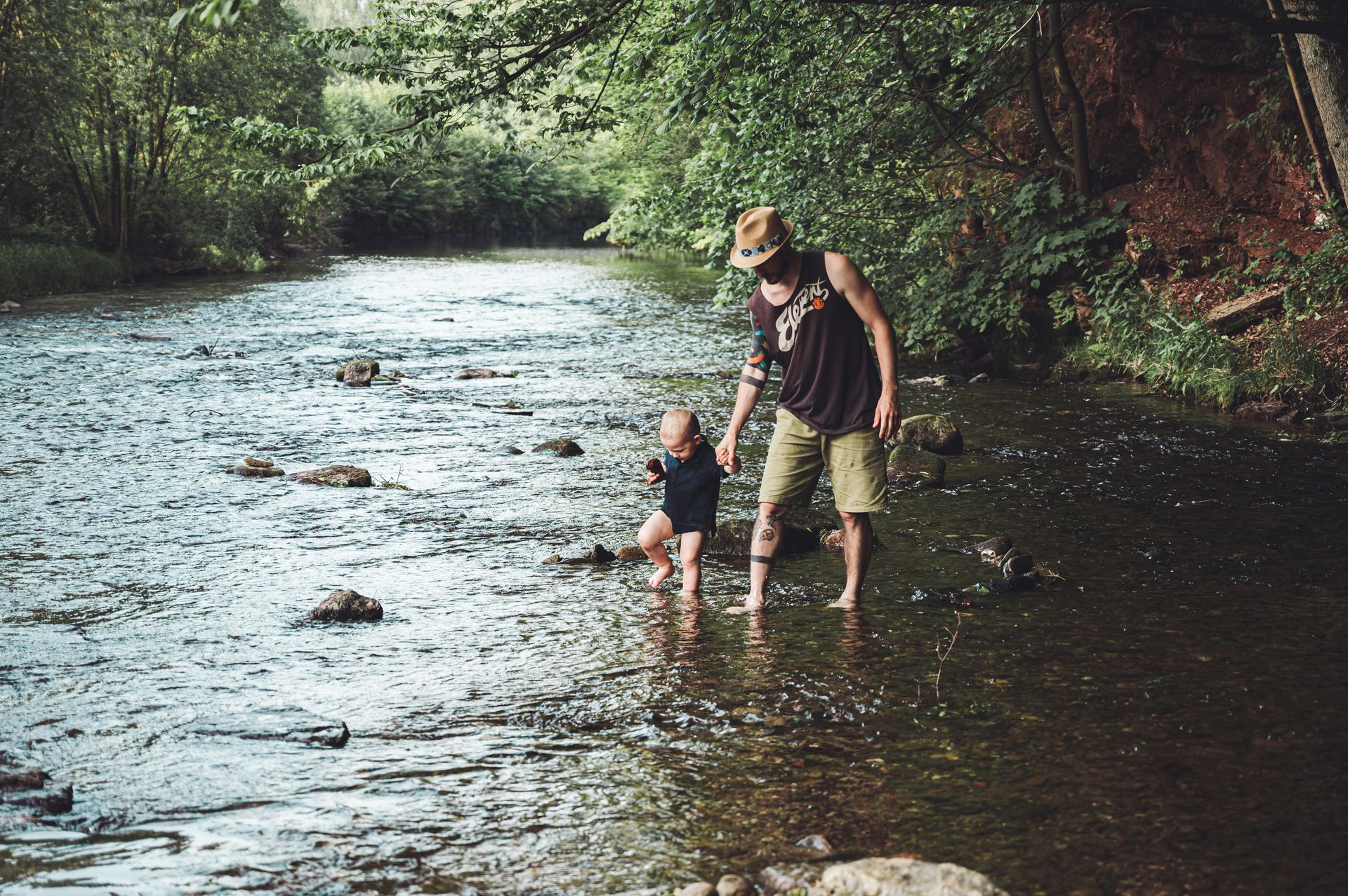 A man and a child are standing in a river.