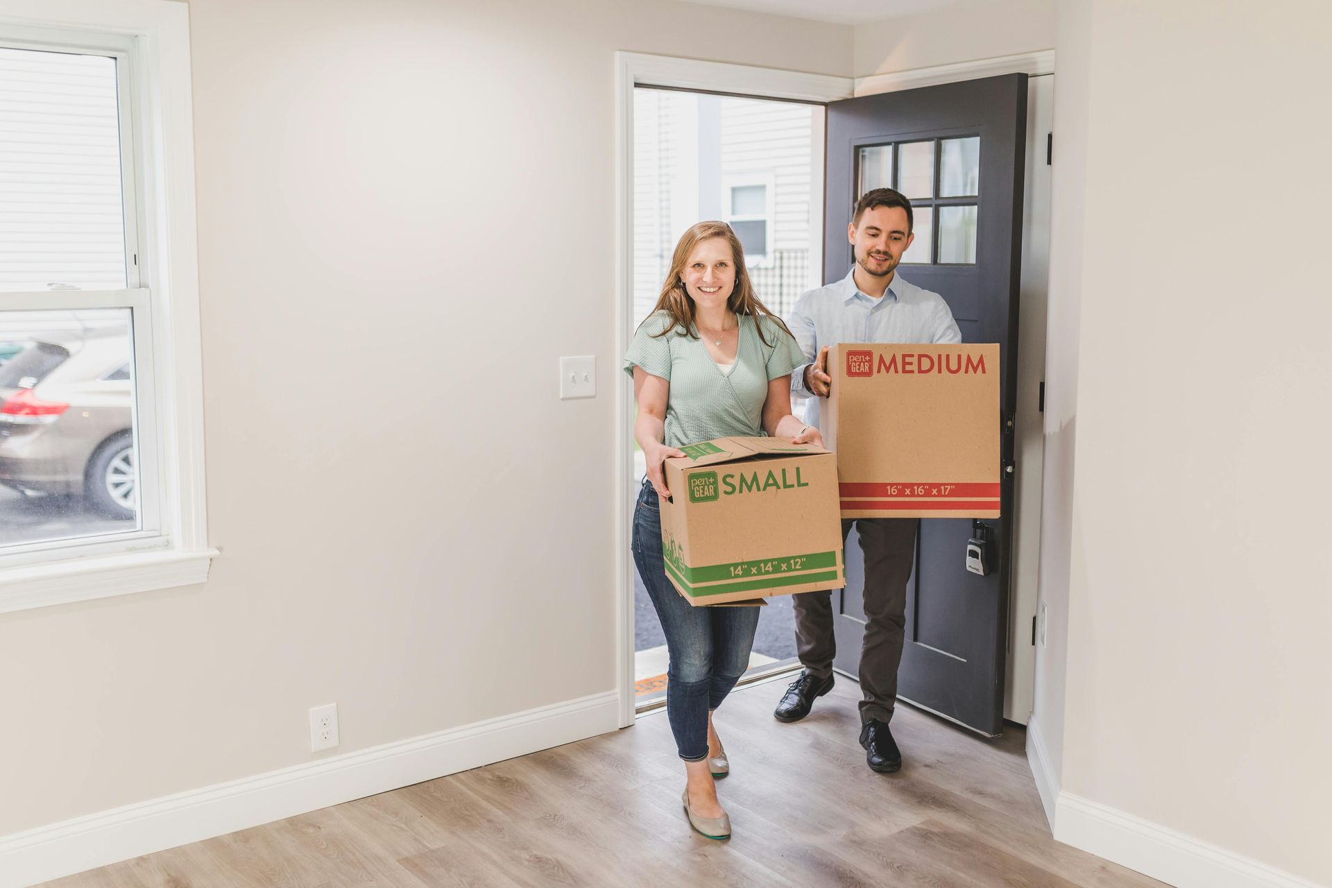 A family is moving into a new home carrying cardboard boxes.