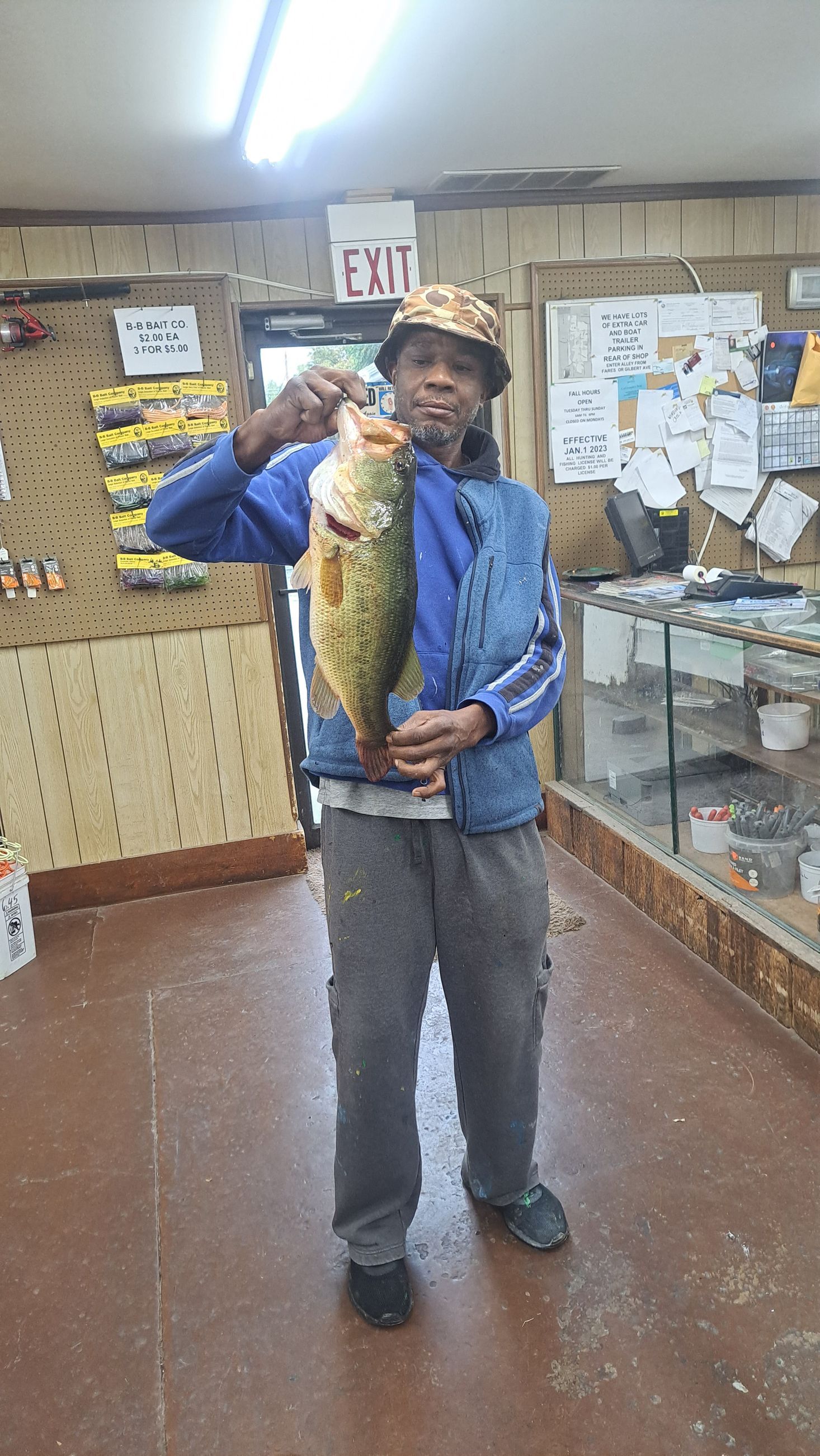 Person holding up a large fish inside a store, posing with a smile.