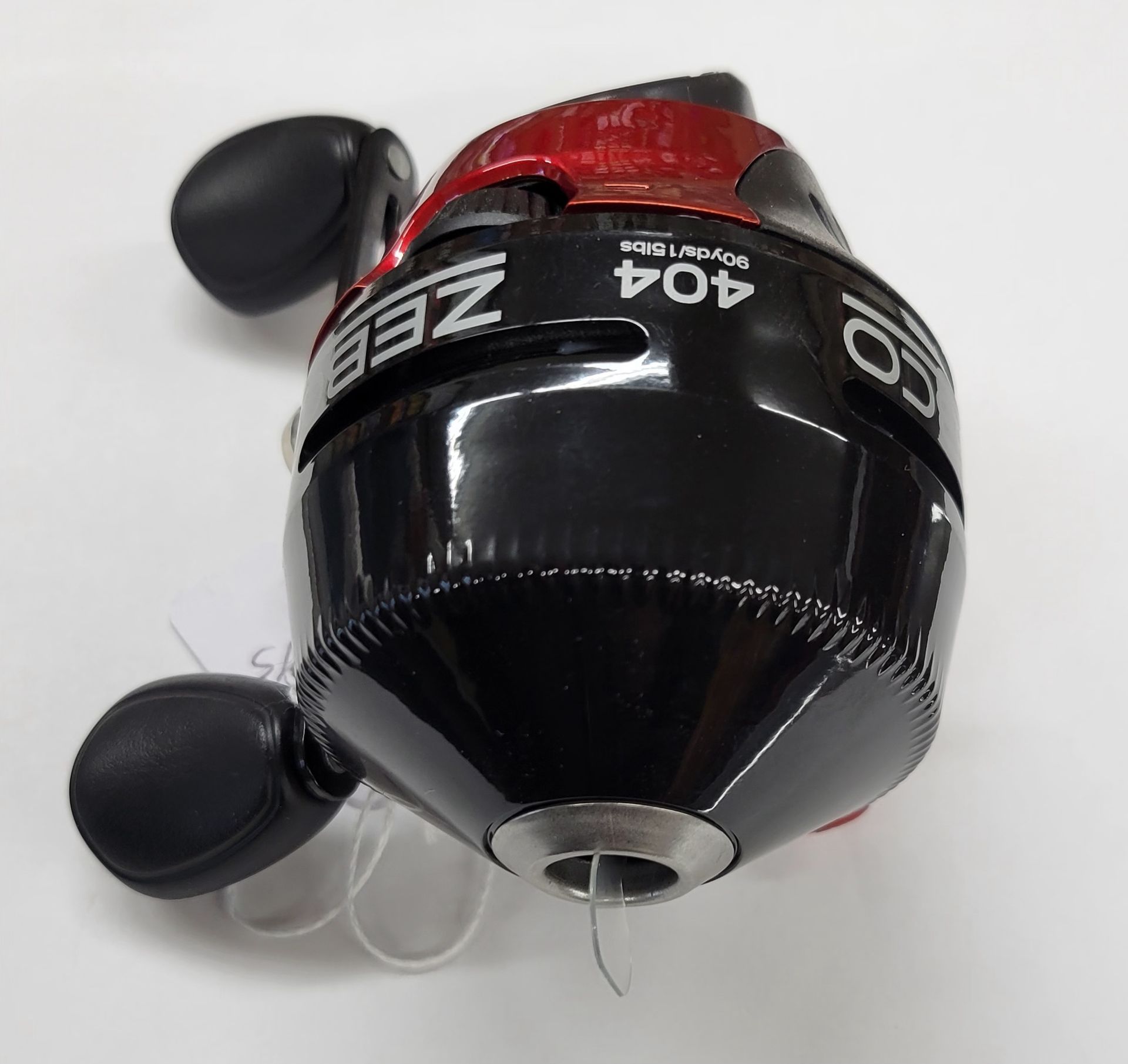 Black and red Zeeba fishing reel with two black handles, angled view.