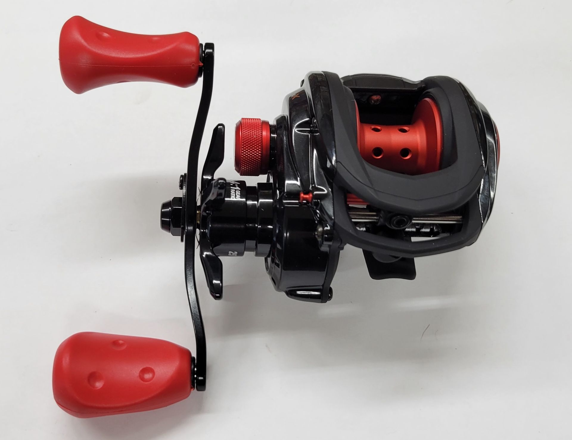 Black and red baitcasting fishing reel with red handles, against a white background.