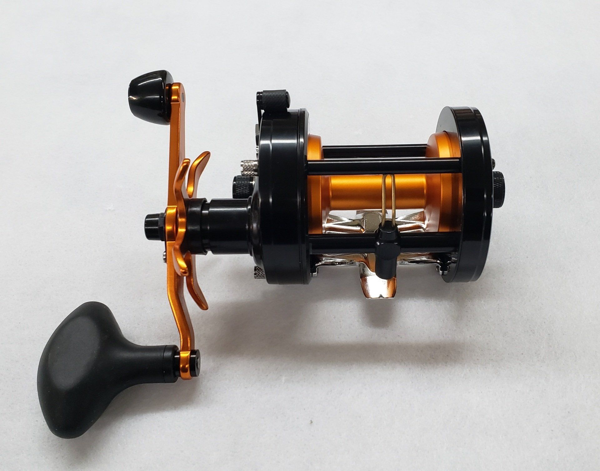 Black and gold fishing reel with a black handle.