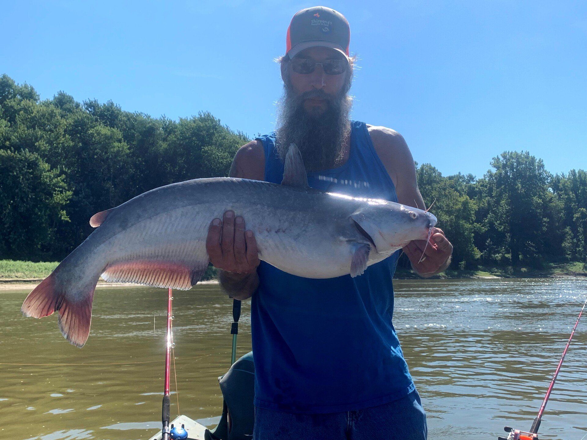Man holding large blue catfish caught while fishing on river.