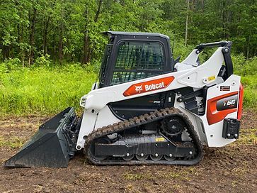 A bobcat track loader is sitting on top of a dirt field.