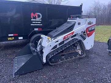 A bulldozer is parked in front of a dumpster.