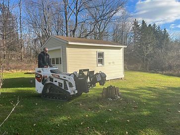 A man is standing next to a stump grinder in a yard.