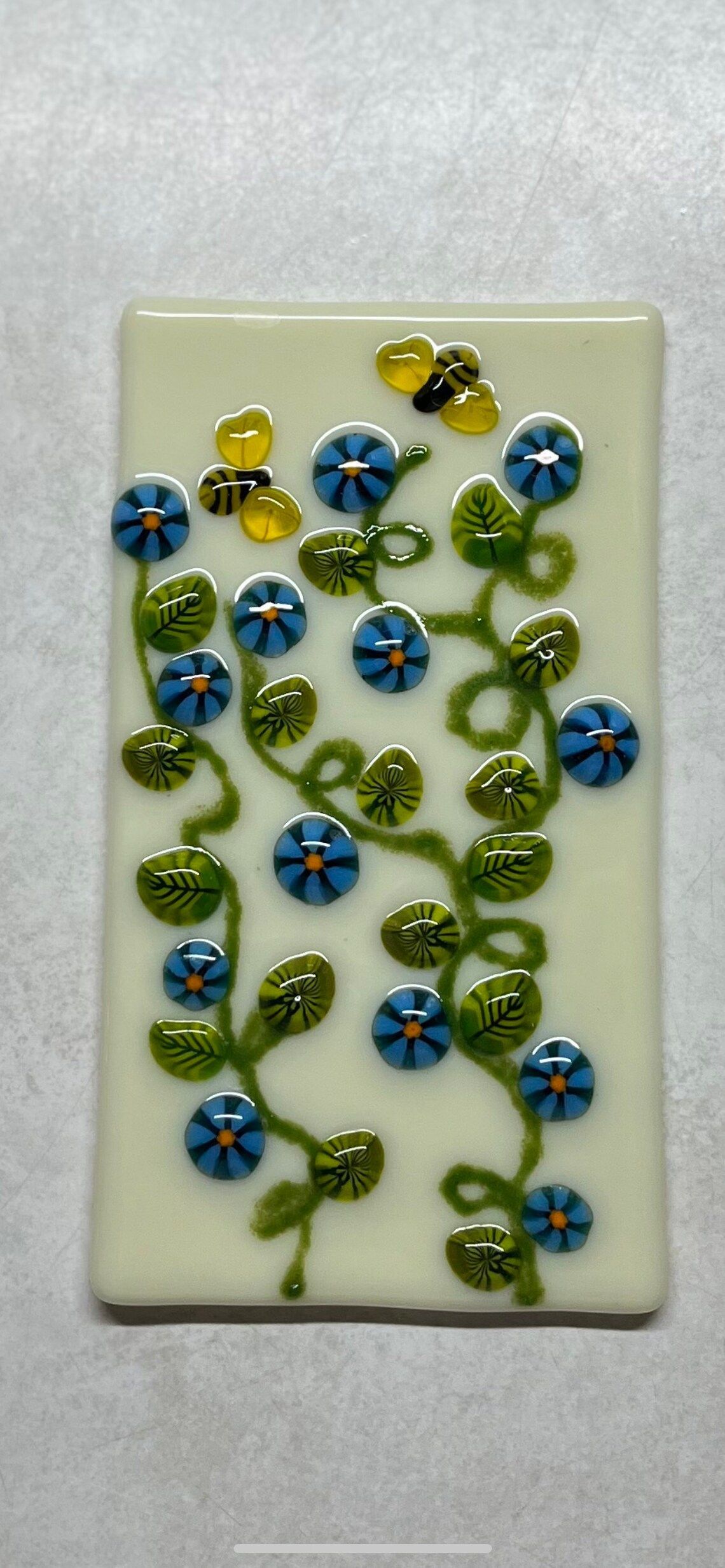 A white plate with blue flowers and bees on it.