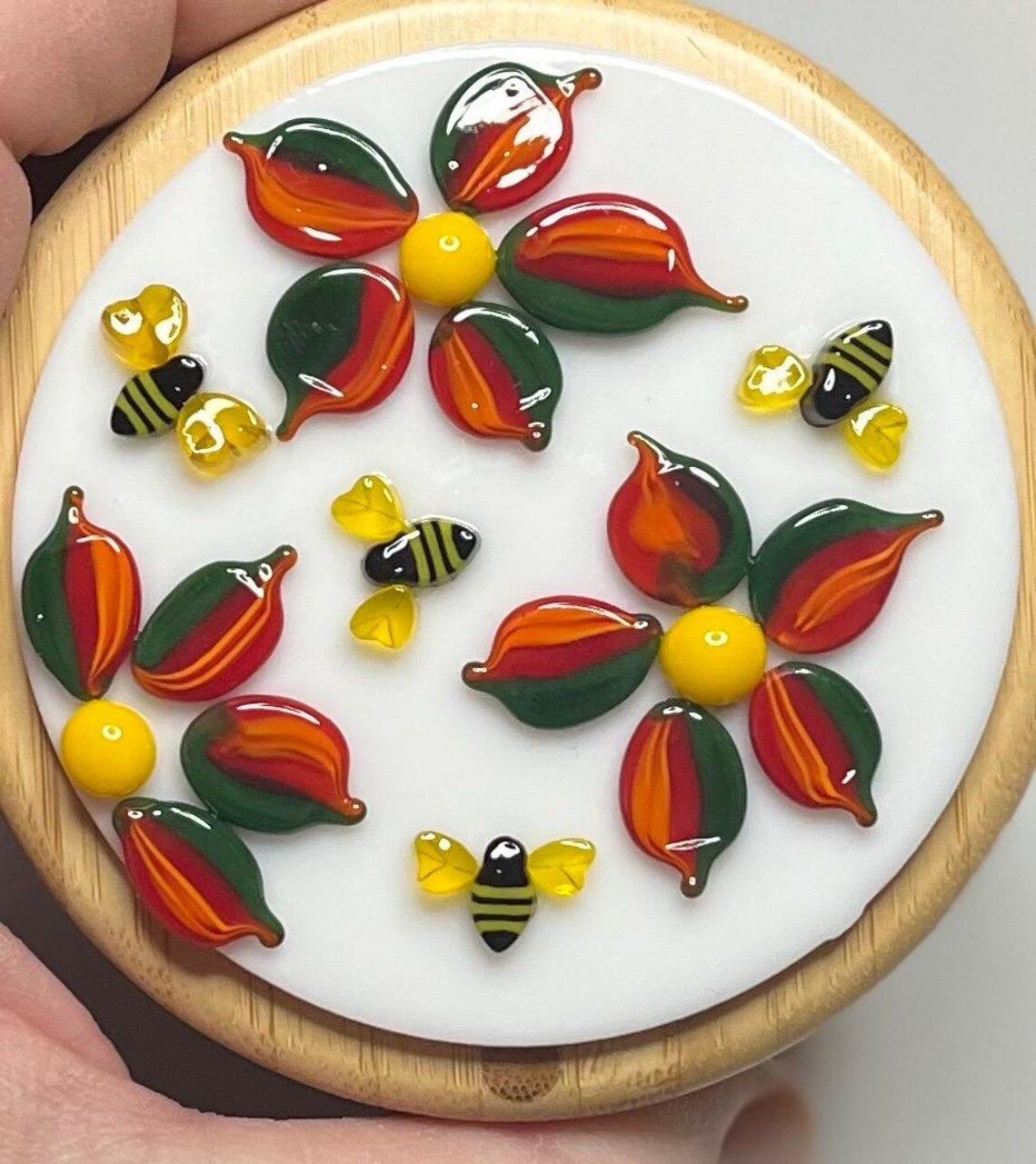 A person is holding a cookie with flowers and bees on it