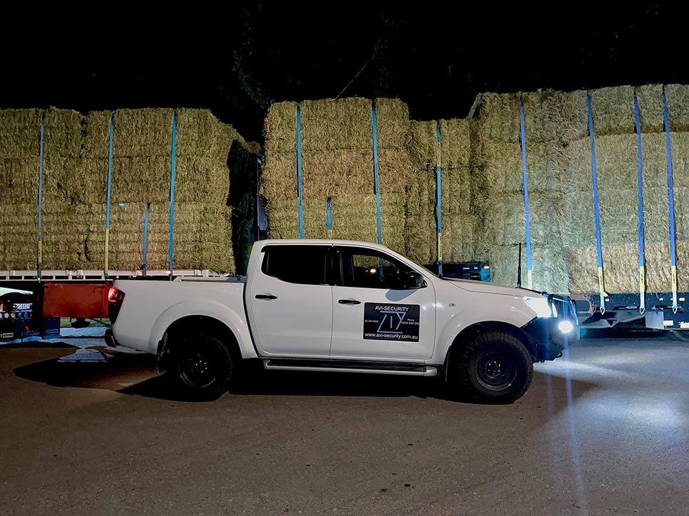 A White Truck is Parked in Front of a Pile of Hay Bales — AVI Protection Group Pty Ltd in West Kempsey, NSW