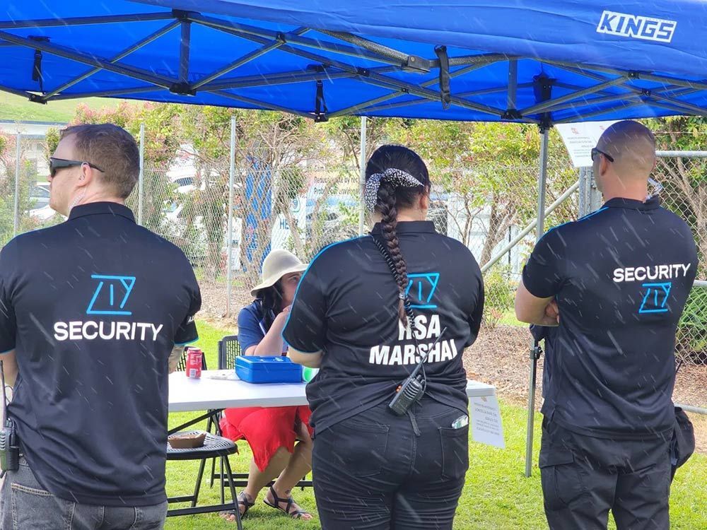 A Group of Security Officers are Standing Under a Blue Tent — AVI Protection Group Pty Ltd in West Kempsey, NSW