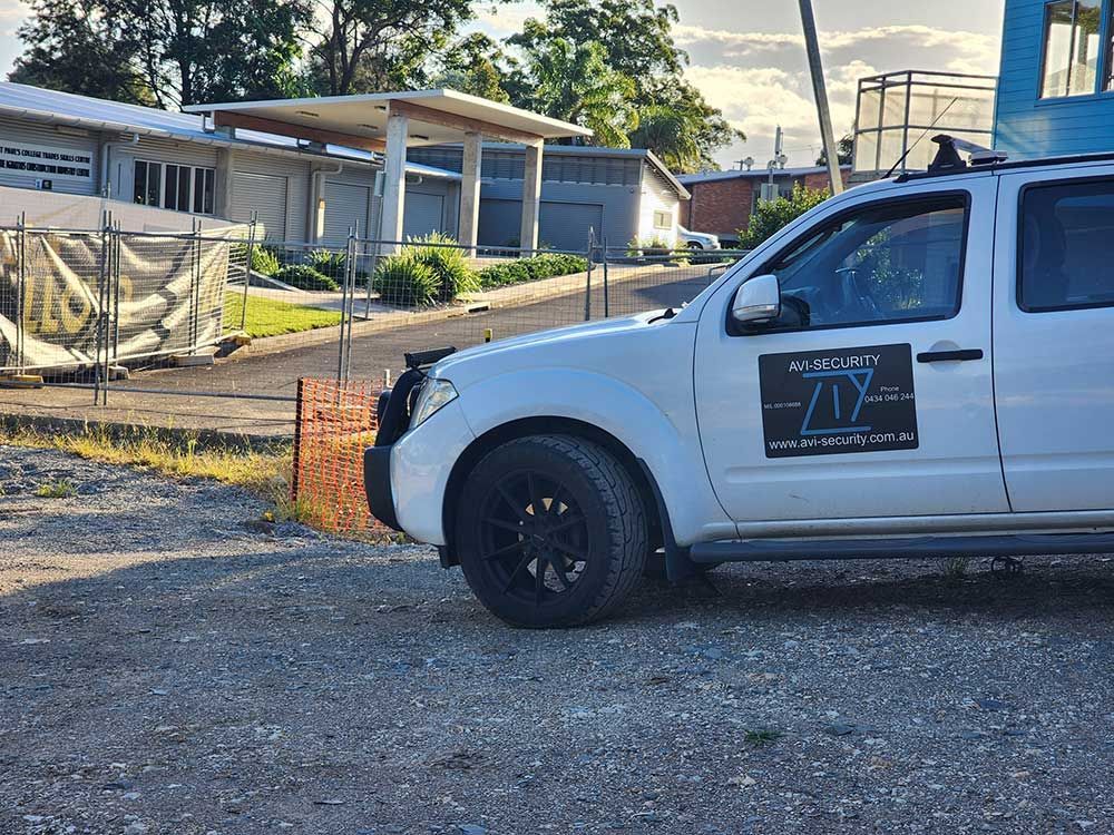 A White Truck is Parked in a Gravel Lot in Front of a Building — AVI Protection Group Pty Ltd in West Kempsey, NSW