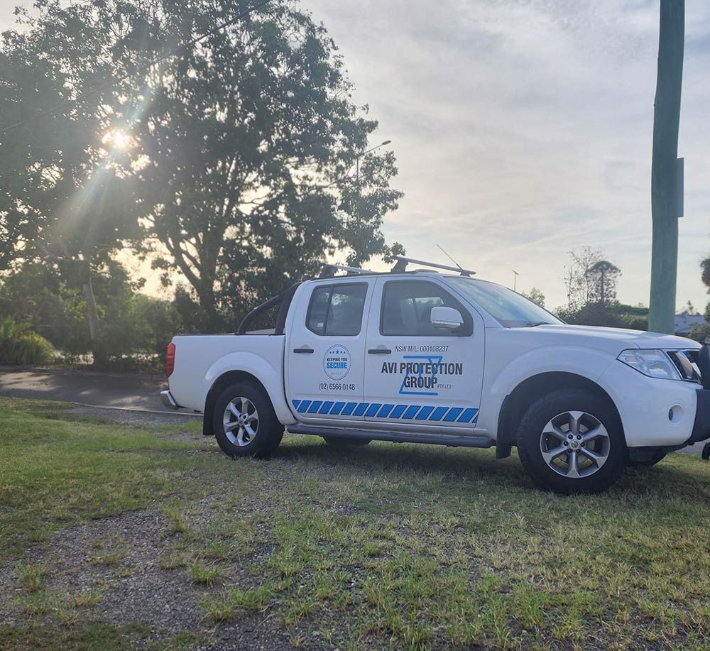A White Pickup Truck is Parked in a Grassy Area — AVI Protection Group Pty Ltd in West Kempsey, NSW
