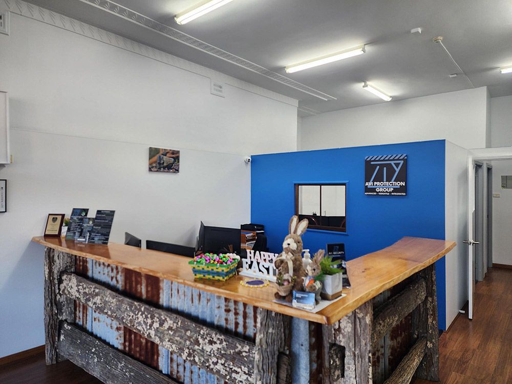 A Reception Area With a Wooden Counter and a Blue Wall — AVI Protection Group Pty Ltd in West Kempsey, NSW