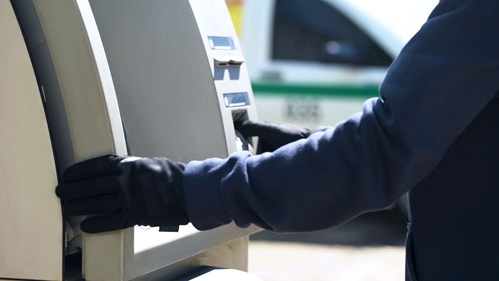 A Person Wearing Black Gloves is Using an Atm Machine — AVI Protection Group Pty Ltd in West Kempsey, NSW
